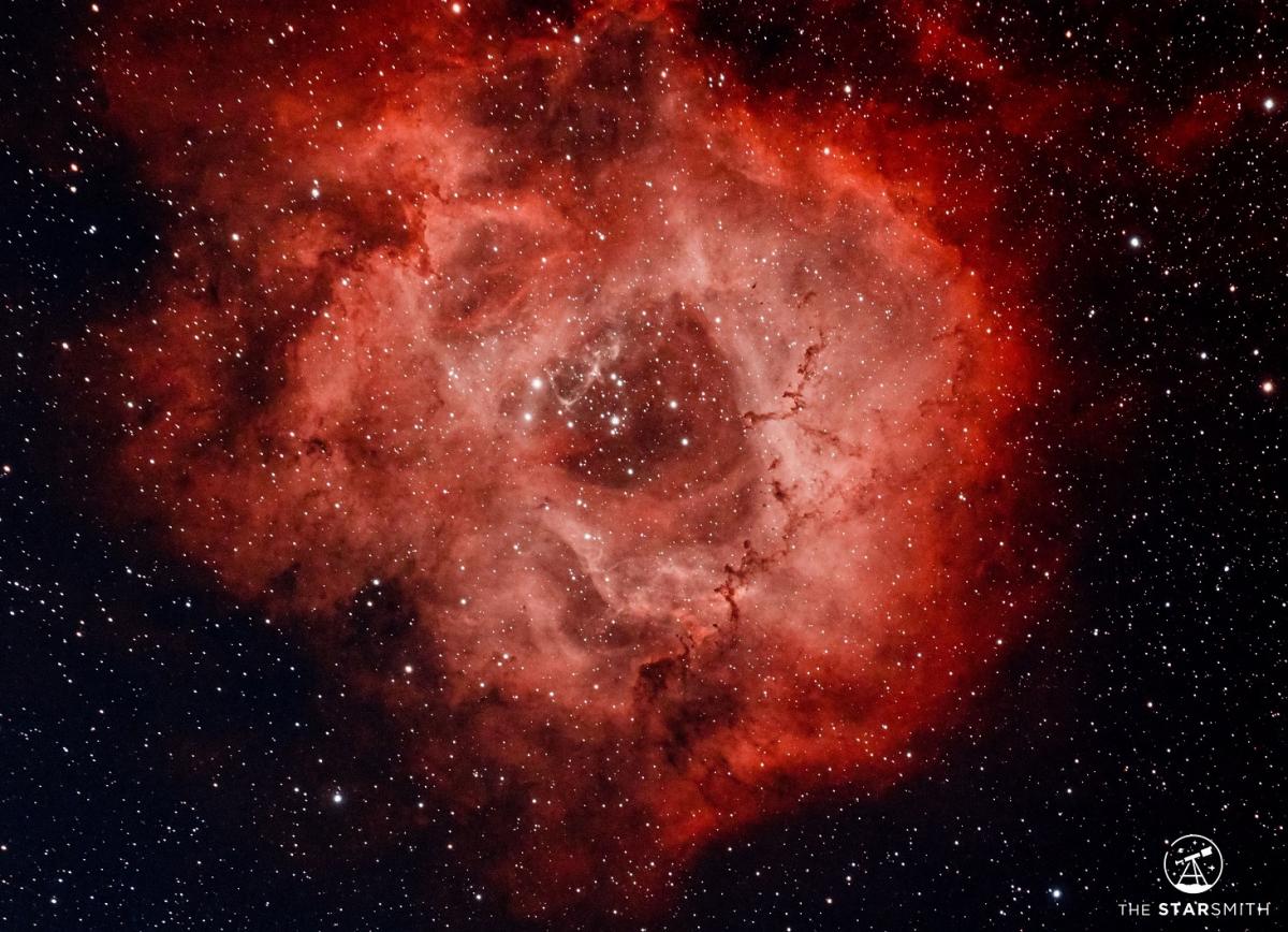 Astro-photography of red Rosette against dark sky background.